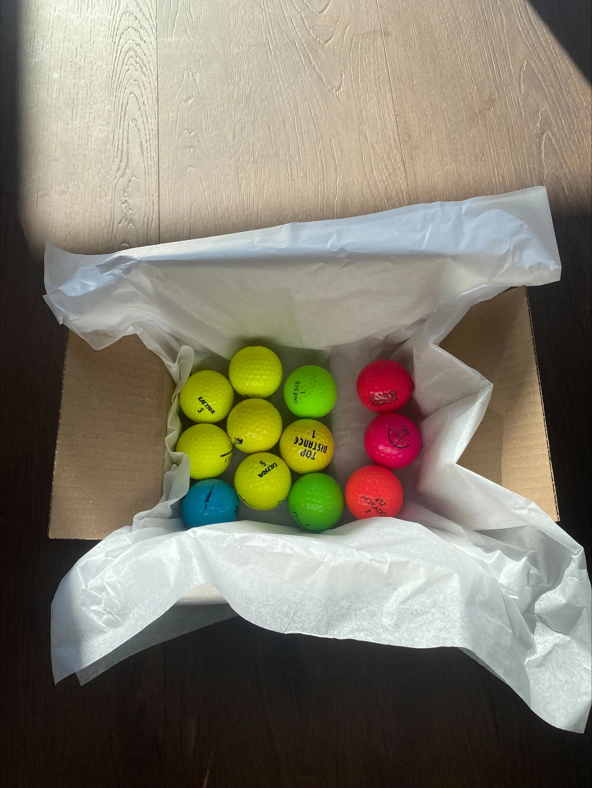 Bunte Golfbälle im Versandkarton mit Seidenpapier, fertig verpackt